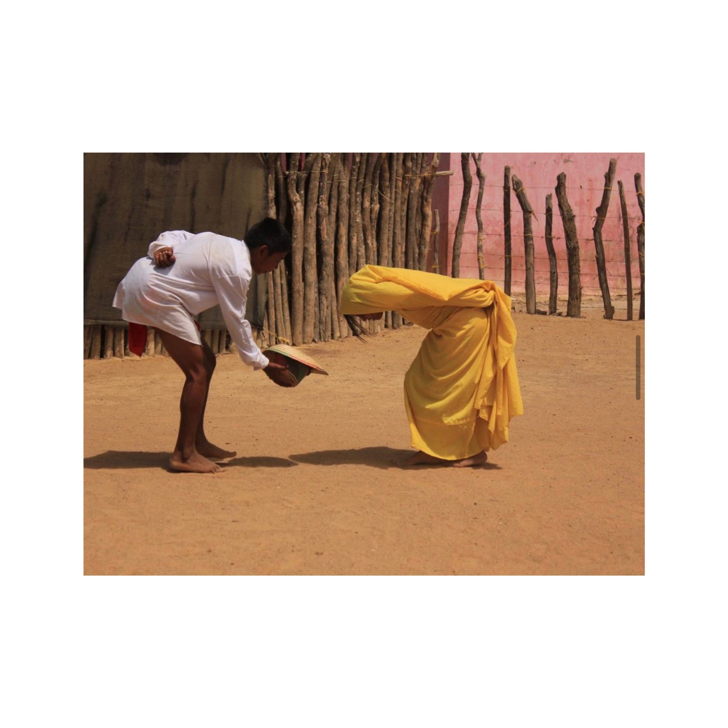 immagine della danaza wayuu Majayura con un uome che porge il suo cappello alla compagna , entrambi indossano abiti tradizionali ballando nel deserto colombiano