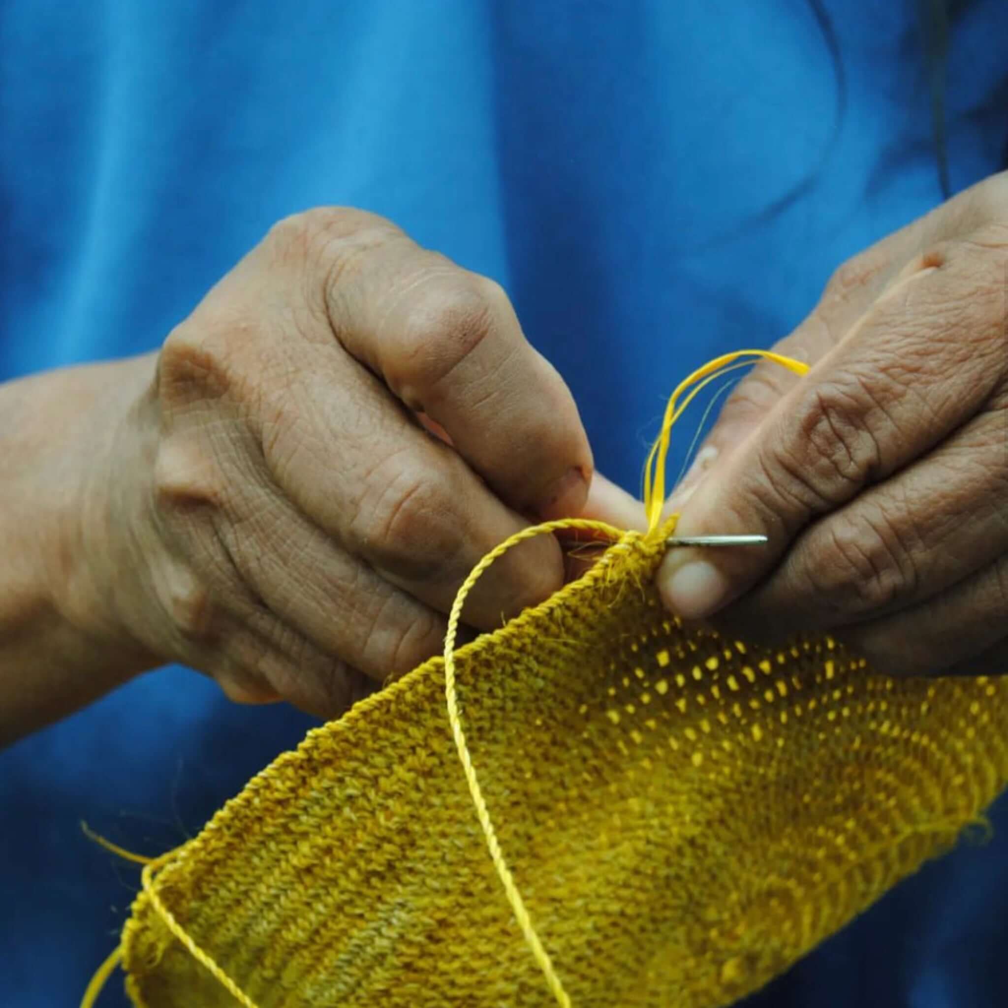 mani che intrecciano la FIBI Bag Solana, borsa ocra sostenibile fatta a mano in Colombia