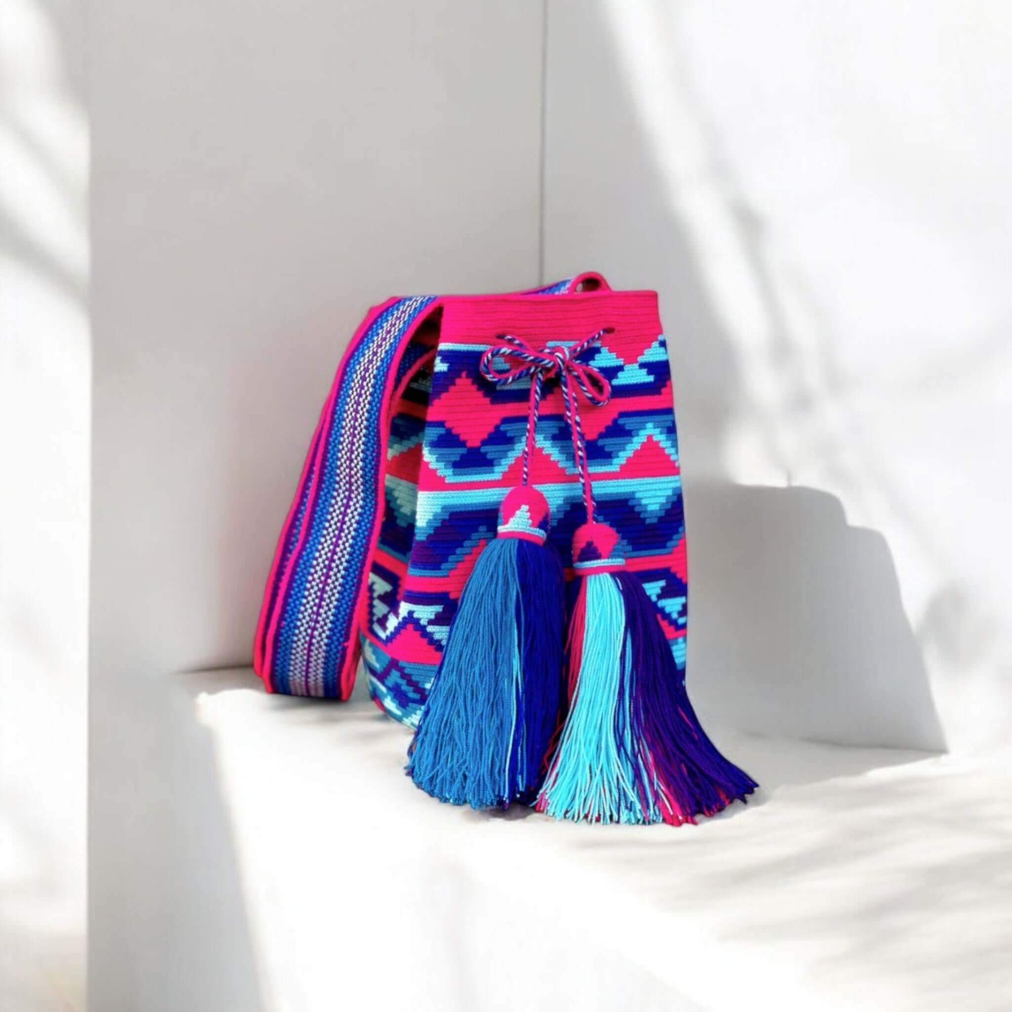 Mochila Wayuu a filo singolo con intreccio fucsia e azzurro, tracolla artigianale e nappine fatte a mano