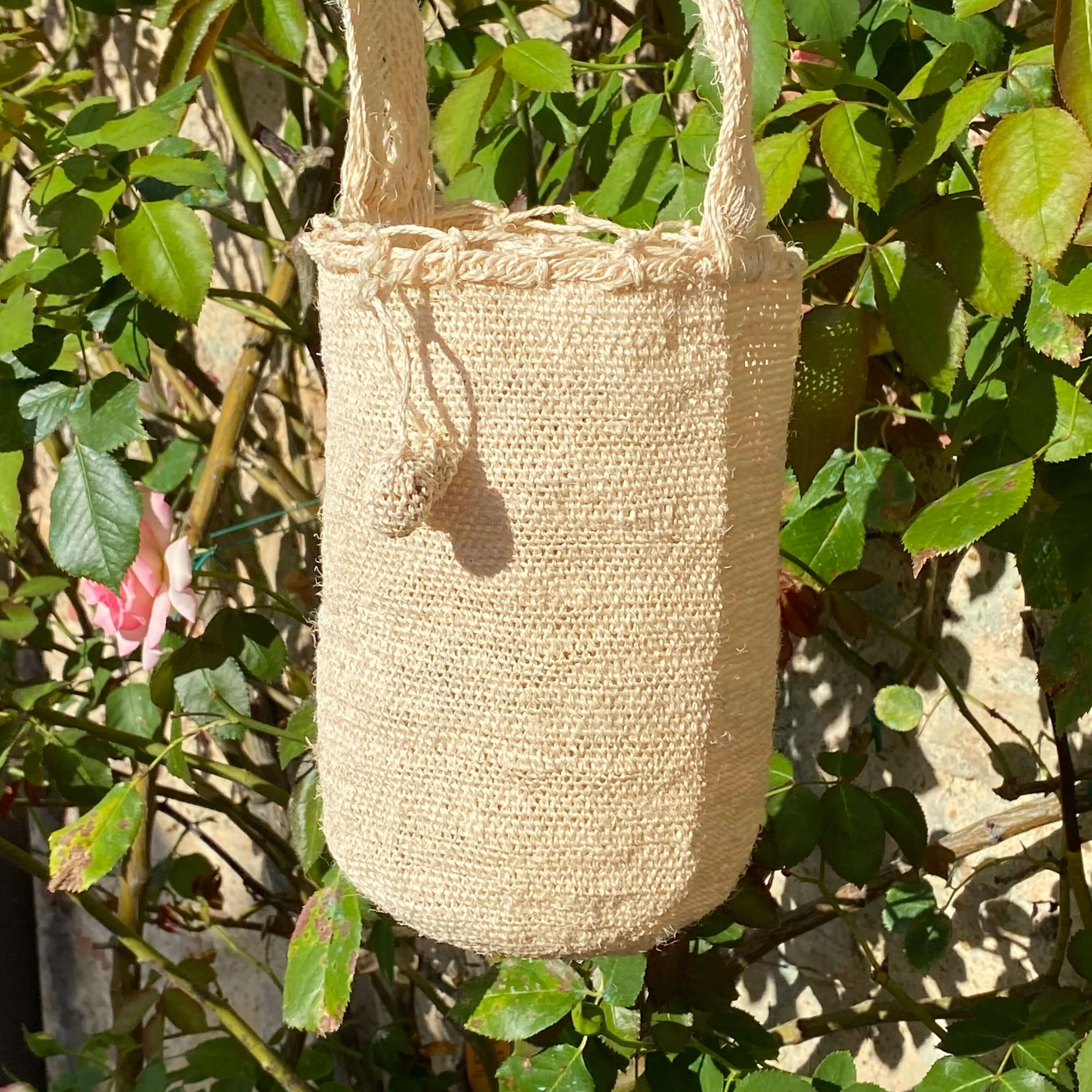 Borsa FIBI Avorio S su sfondo con fiori e rose rosa – borsa sostenibile in fique artigianale colombiana, elegante e naturale