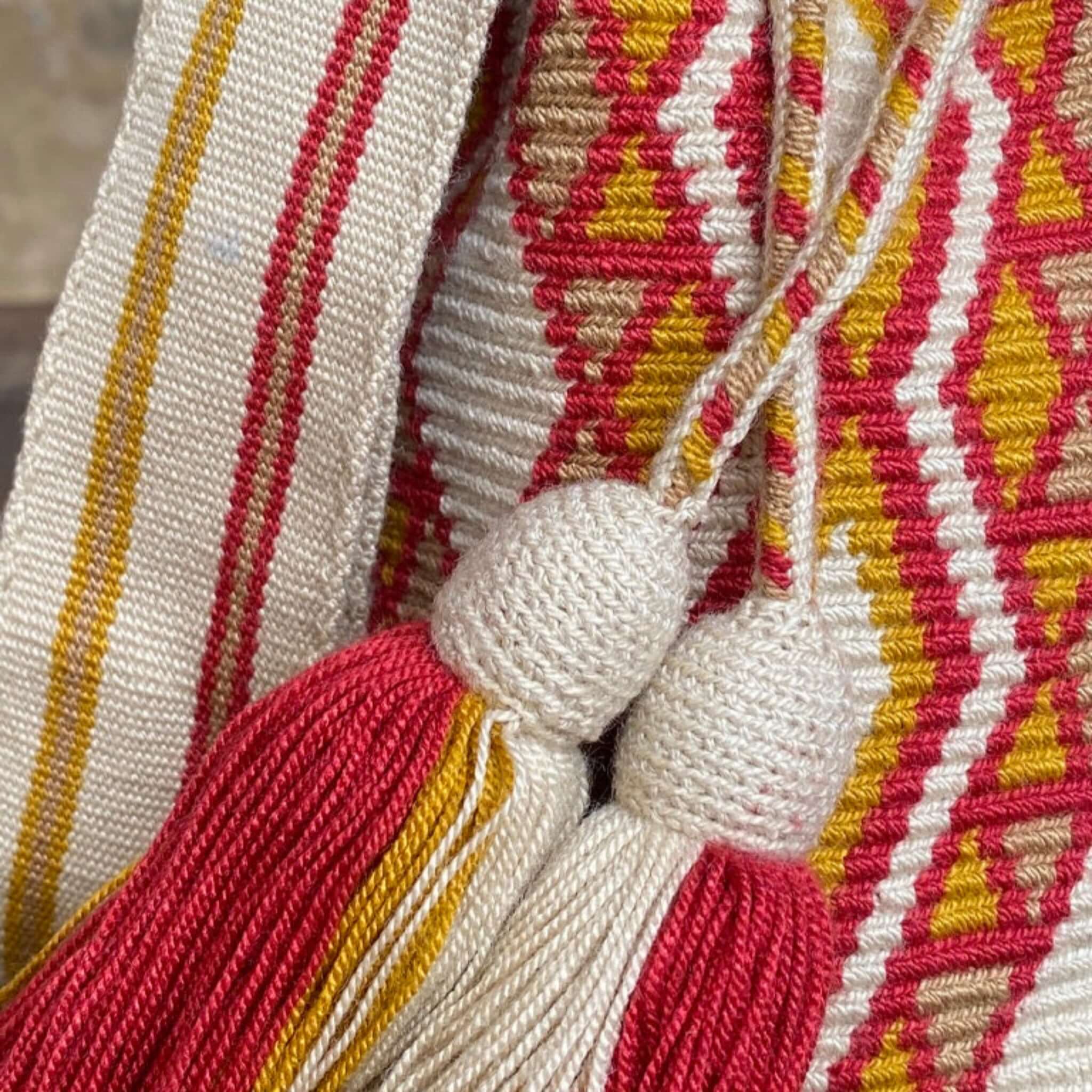 Dettaglio nappine e tracolla larga della Mochila beige chiaro con disegni Wayuu