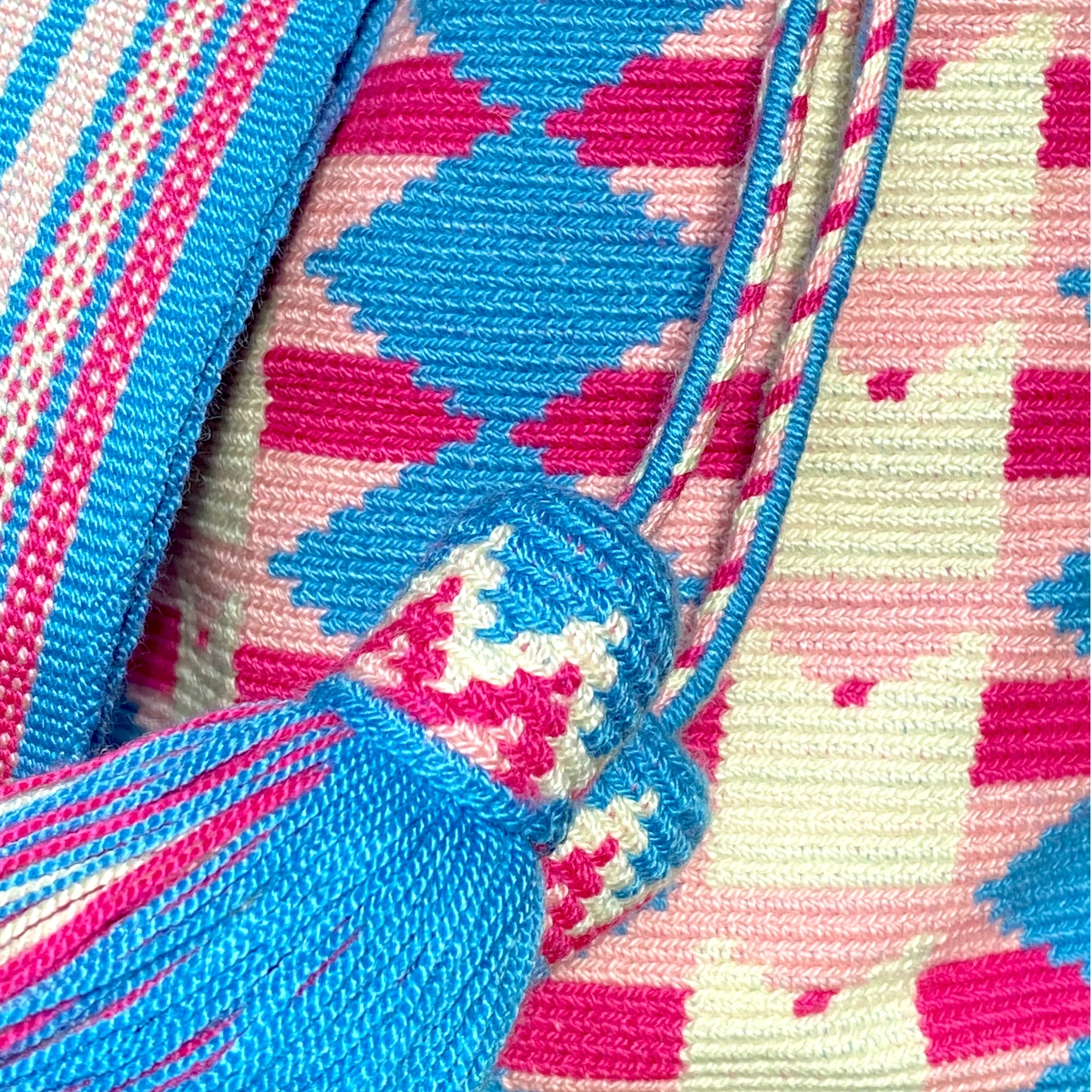 Dettaglio borsa Clim , nappine e lavorazione artigianale con motivi geometrici in azzurro, bianco, rosa e fucsia fatta a mano in Colombia