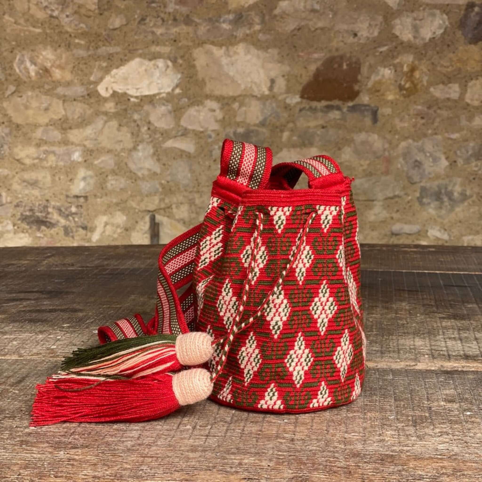 Borsa artigianale colombiana, realizzata all'uncinetto con motivi etnici. Mochila wayuu rossa con intricato disegno tradizionale verde e rosa tenue, nappine