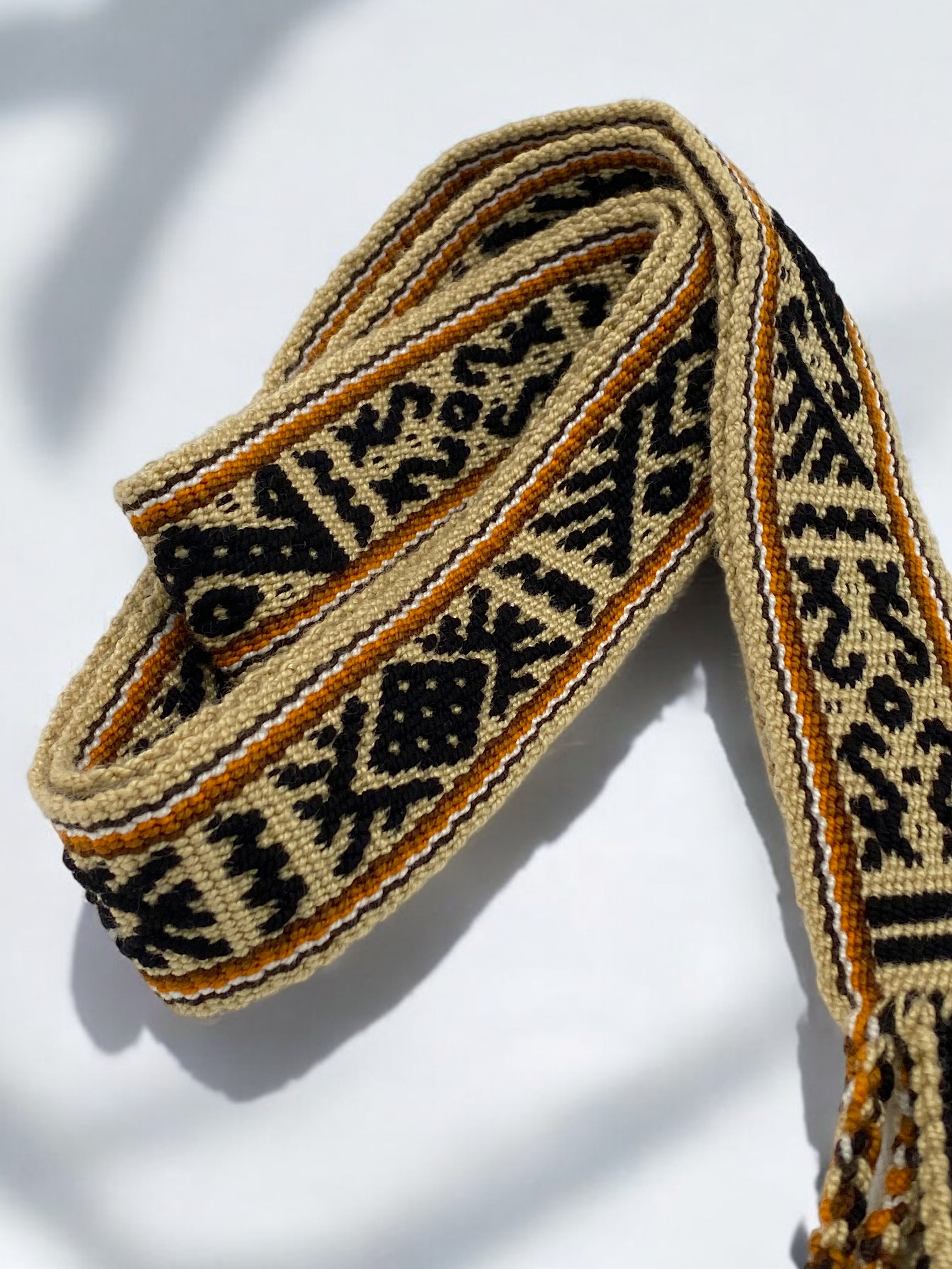 Cintura artigianale tessuta a mano in cotone, colori beige, arancio e nero, realizzata da artigiane colombiane