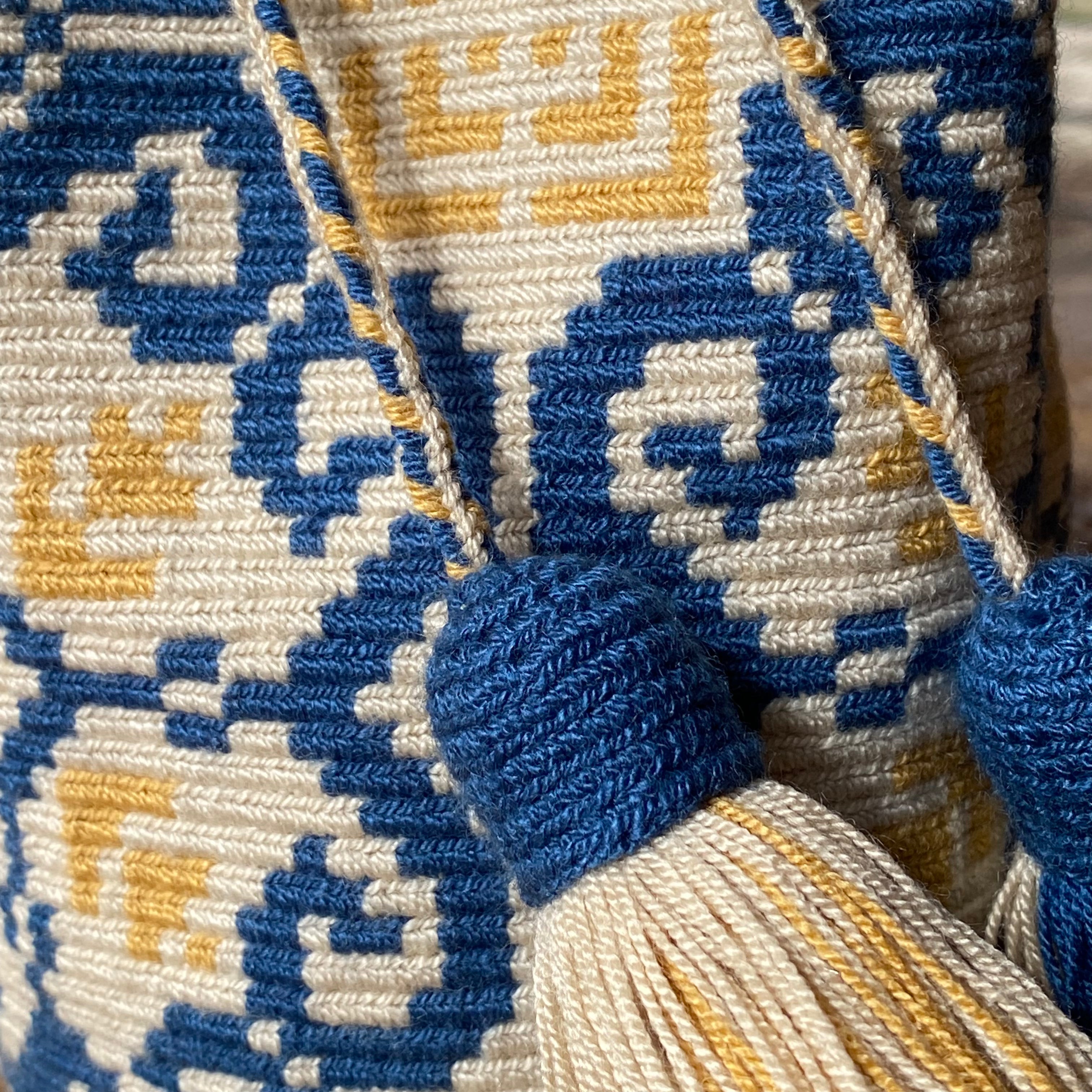 dettaglio nappine e trama della piccola borsa tessuta all'uncinetto con nappine