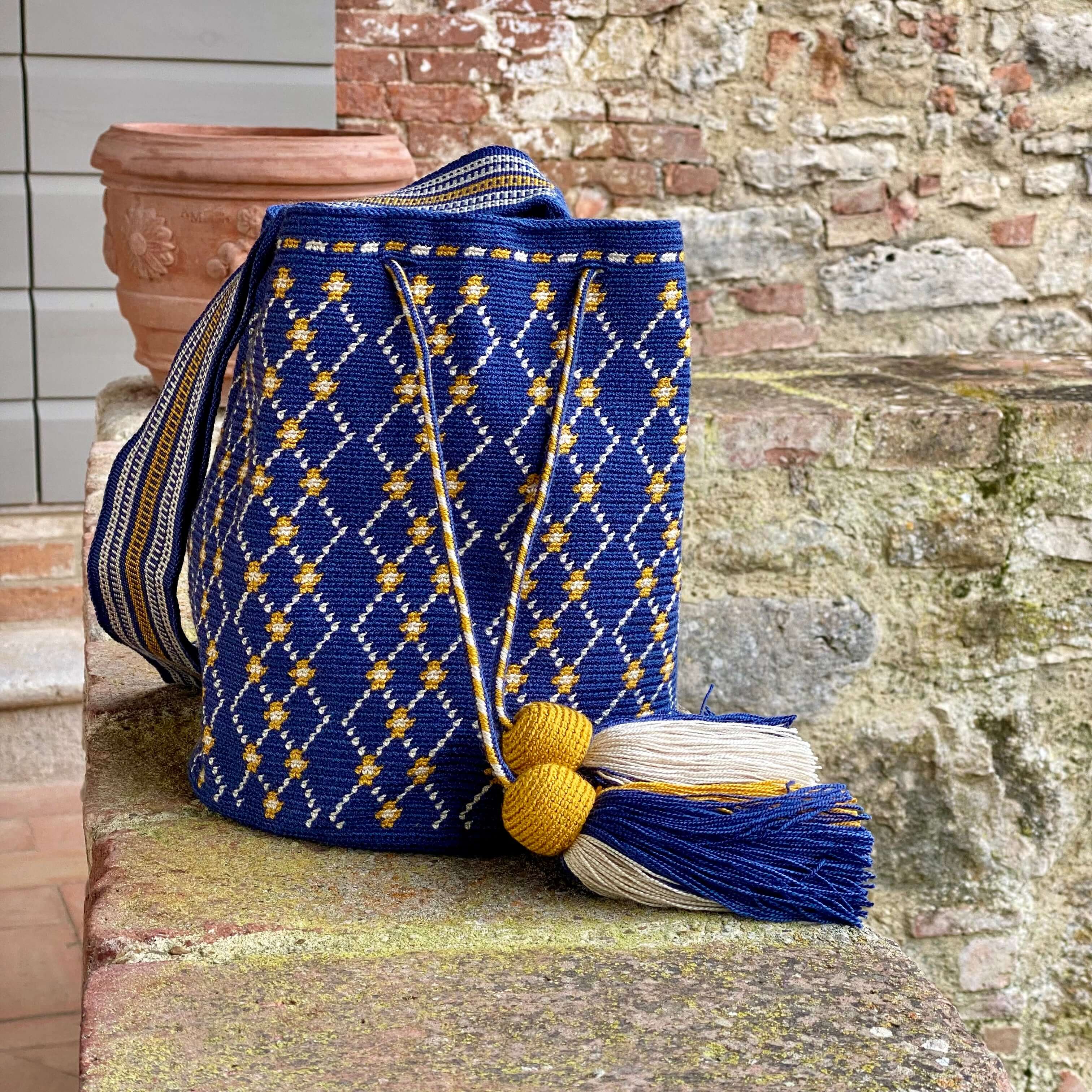 Borsa a secchiello, completamente chiudibile grazie alla coulisse. Raffinato blu accesso con eleganti rombi ocra e bianchi , nappine ocra rifinite minuziosamente, intrecciata a mano.