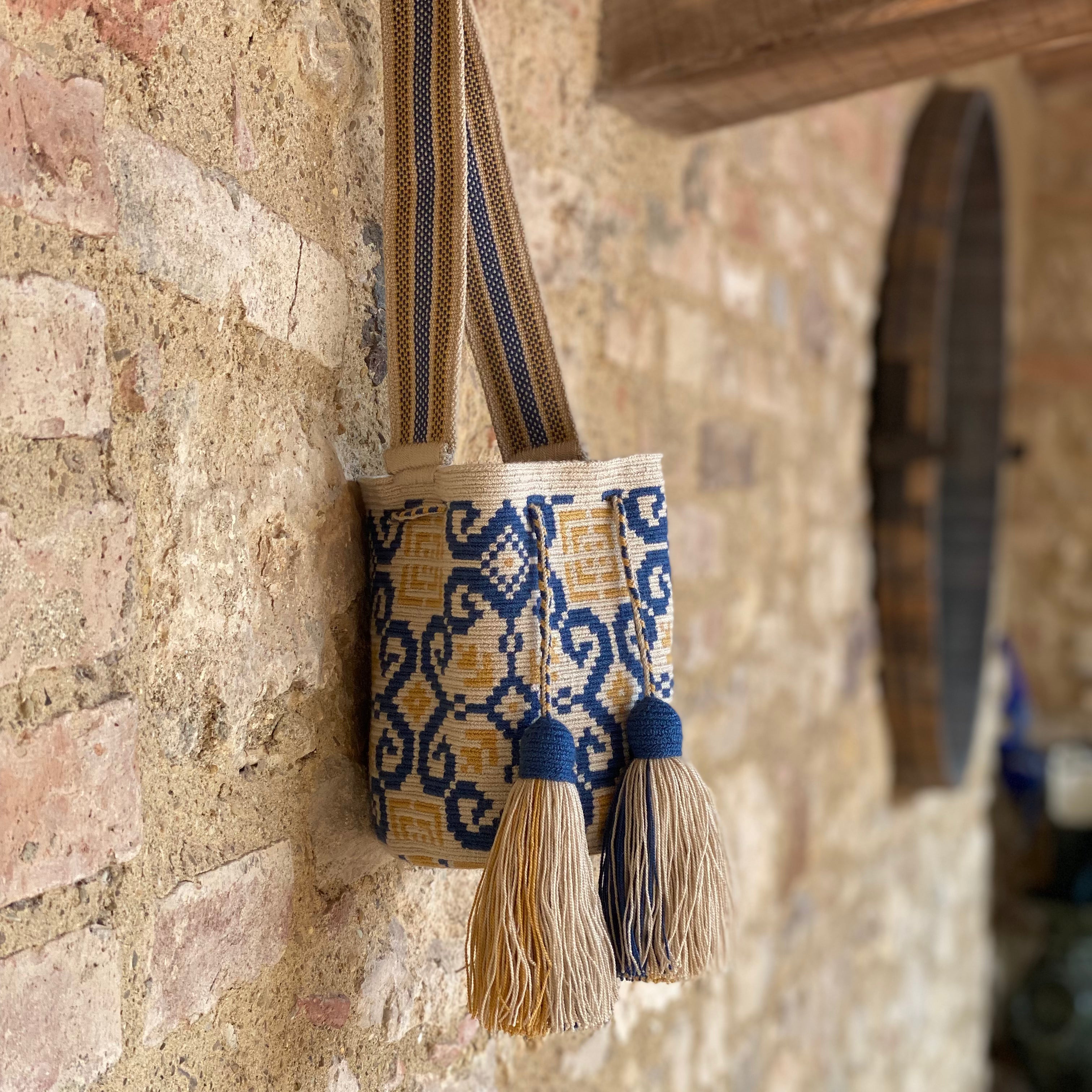 mochila Wayuu piccola con motivi geometrici blu e gialli su fondo beige – Volver Bags