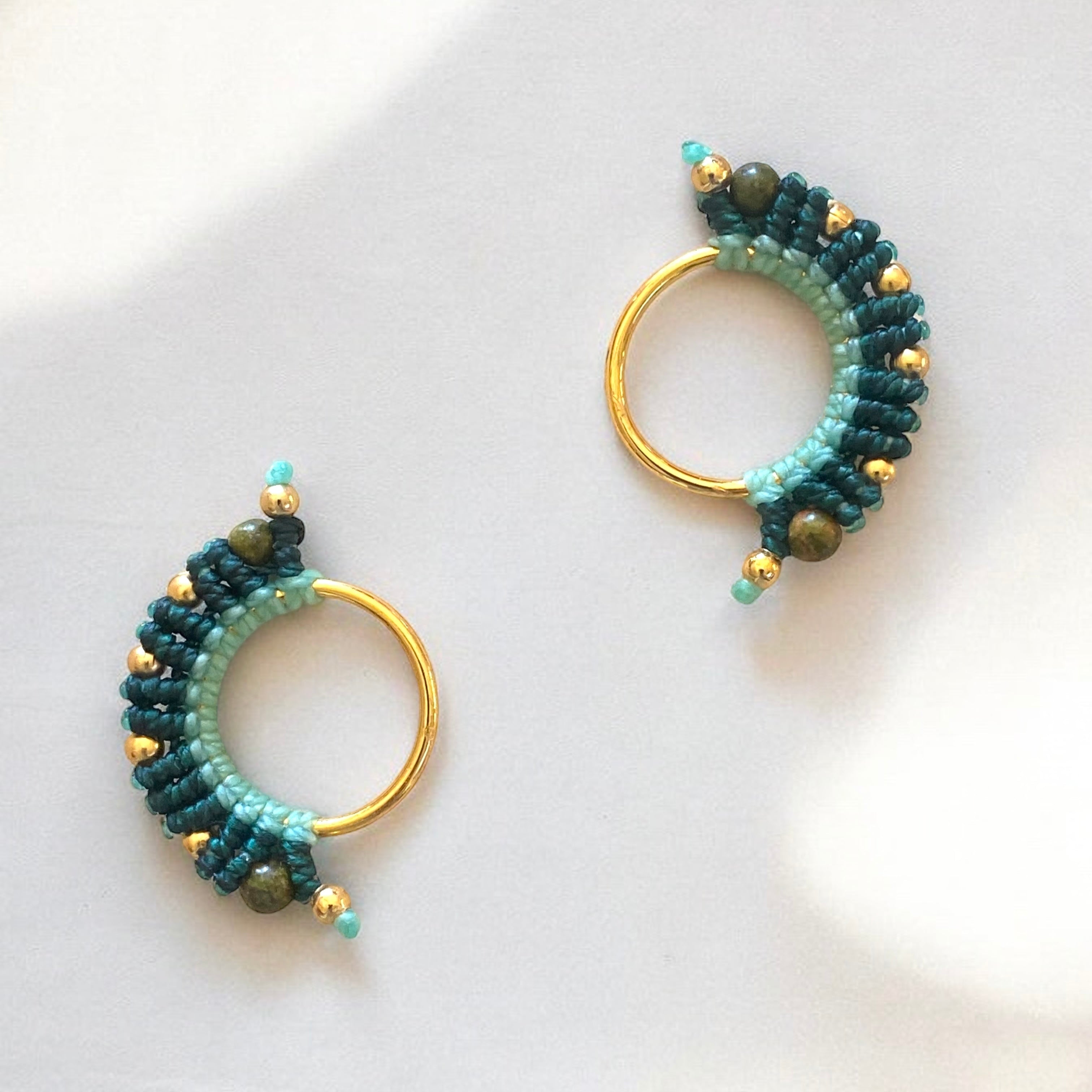 Orecchino macramè con fili di cotone in verde menta chiaro e un verde più intenso, annodato artigianalmente e completato da dettagli dorati.”