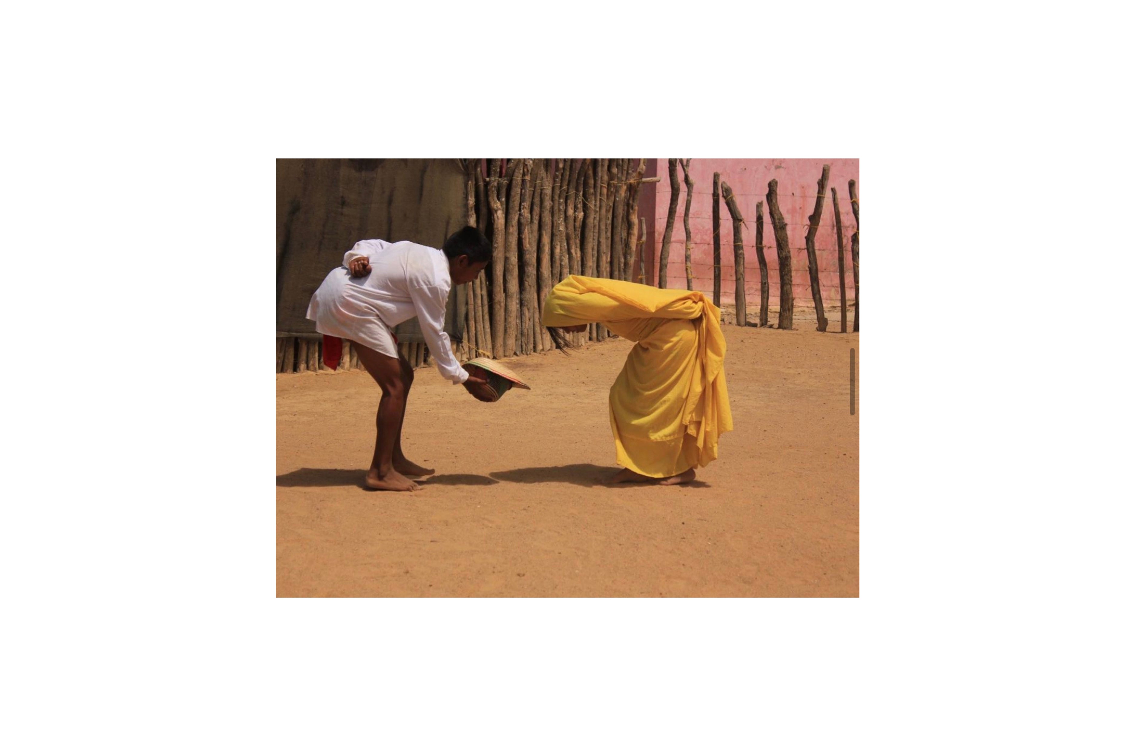 immagine della danaza wayuu Majayura con un uome che porge il suo cappello alla compagna , entrambi indossano abiti tradizionali ballando nel deserto colombiano  