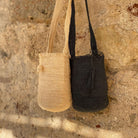 FIBI Bag Seppia S – Borsa artigianale in fibra di fique blu notte , nero profondo, fotografata accanto alla borsa gemella color latte. Sono evidenziate le nappine e la fibra materica della borsa

