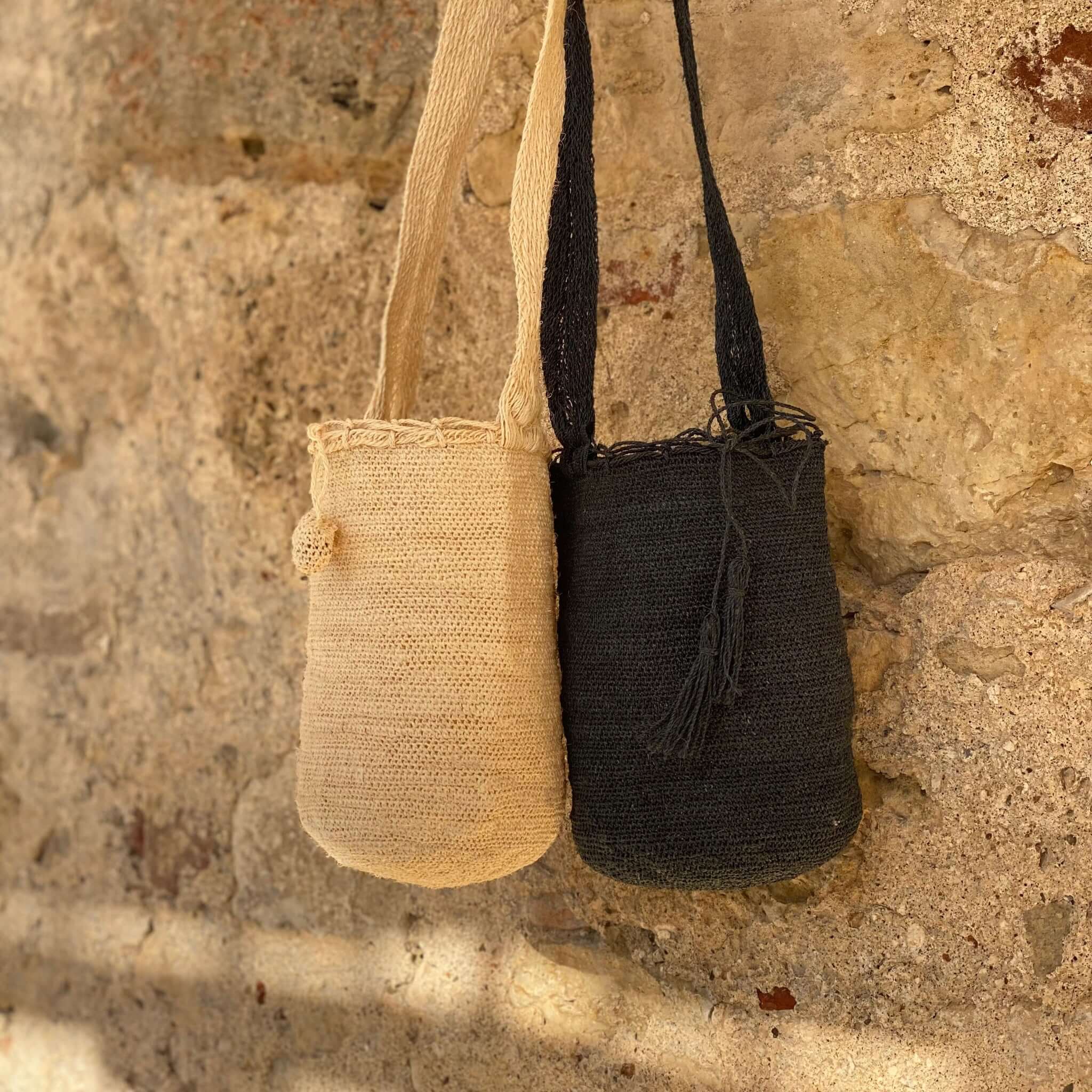 FIBI Bag Seppia S – Borsa artigianale in fibra di fique blu notte , nero profondo, fotografata accanto alla borsa gemella color latte. Sono evidenziate le nappine e la fibra materica della borsa
