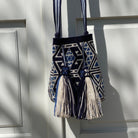 Borsa Wayuu blu e avorio, realizzata a mano in Colombia, fotografata appesa con luce morbida – Volver Bags
