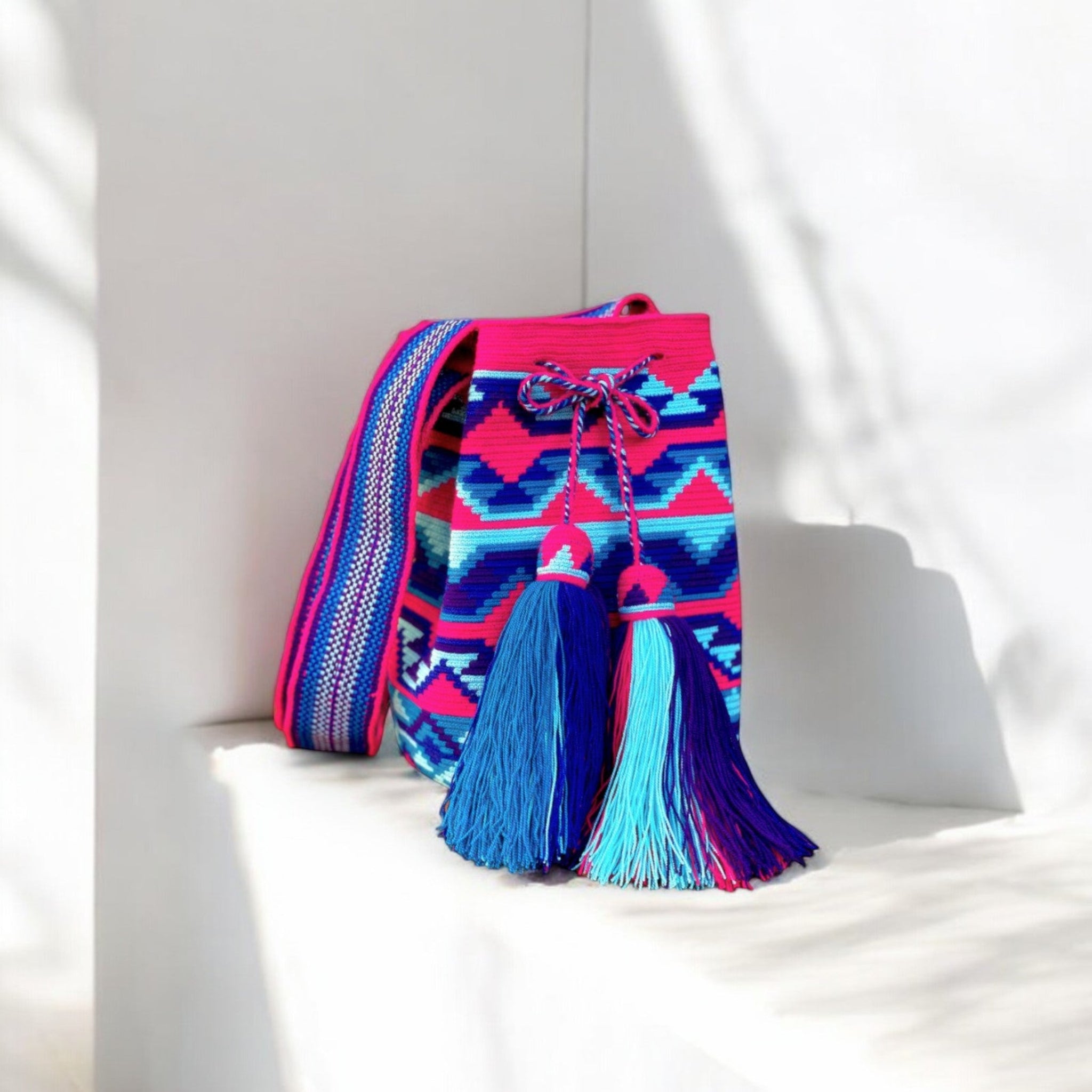  Mochila Buenas: lavorazione a filo singolo, intreccio fucsia e azzurro, simbolo dell’artigianato autentico Wayuu. Nappine rifinite e tracolla tessuta sl telaio a mano