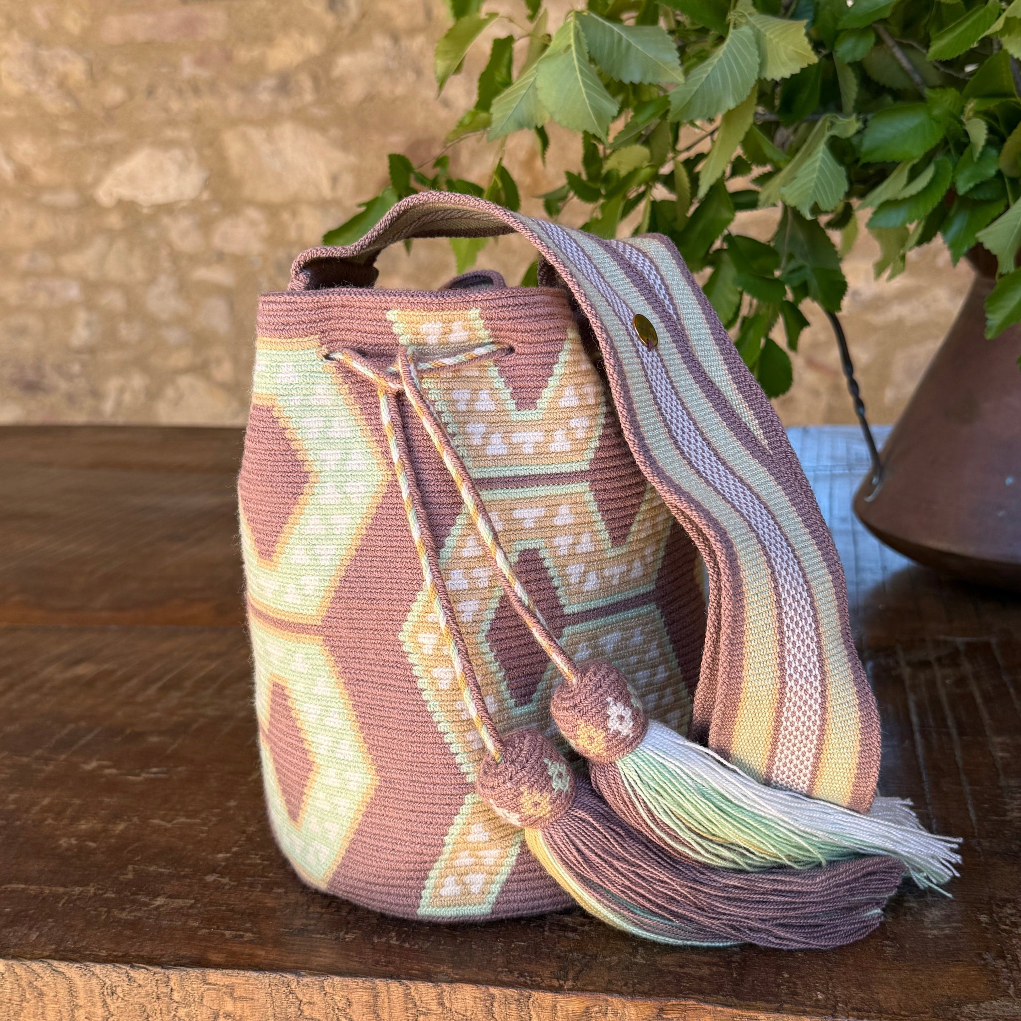     Borsa Wayuu artigianale Mochila Classic Serena nei colori malva e verde salvia con tracolla intrecciata e dettagli geometrici.