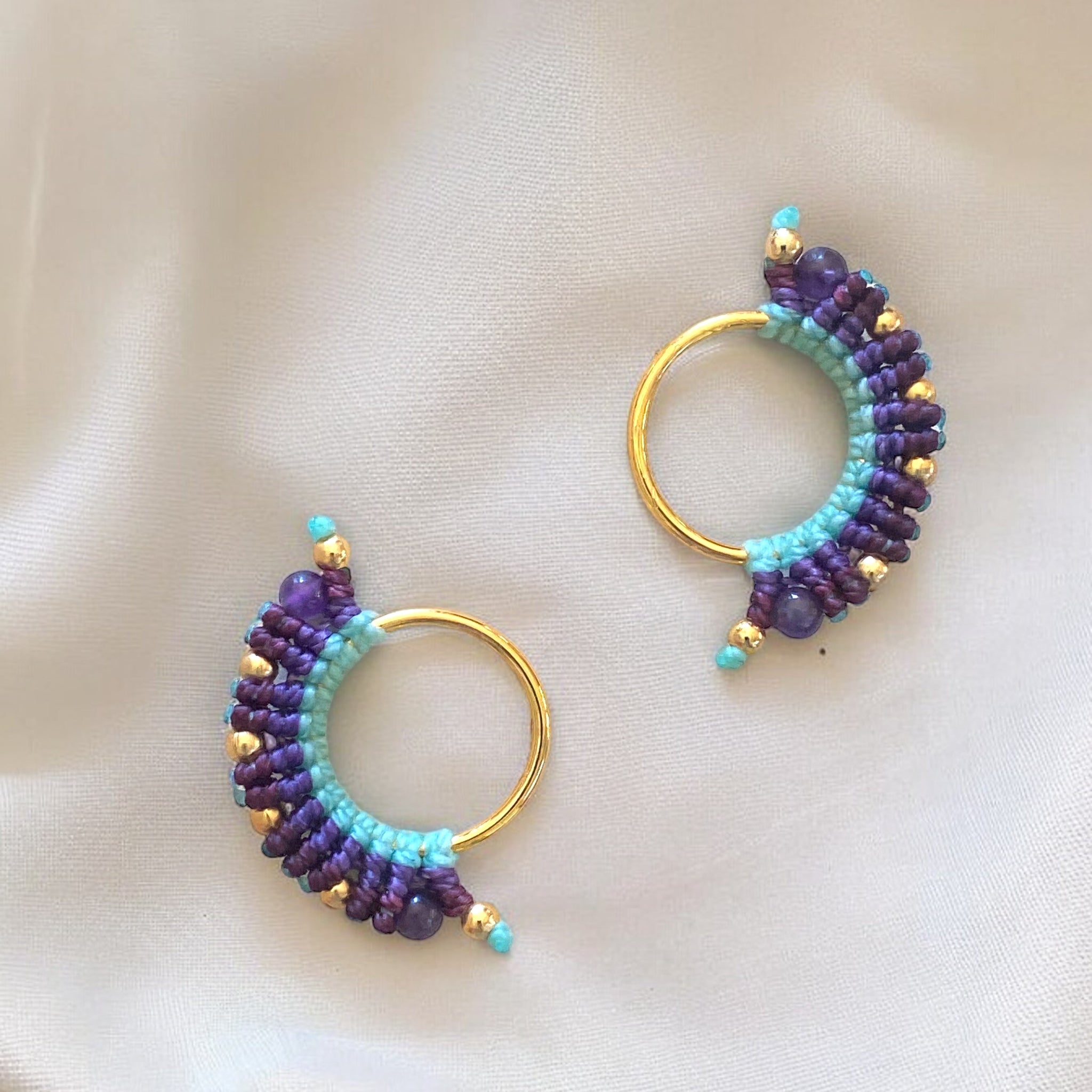 orecchino artigianale colombiano con fili azzurri e due tonalità di viola, montatura dorata