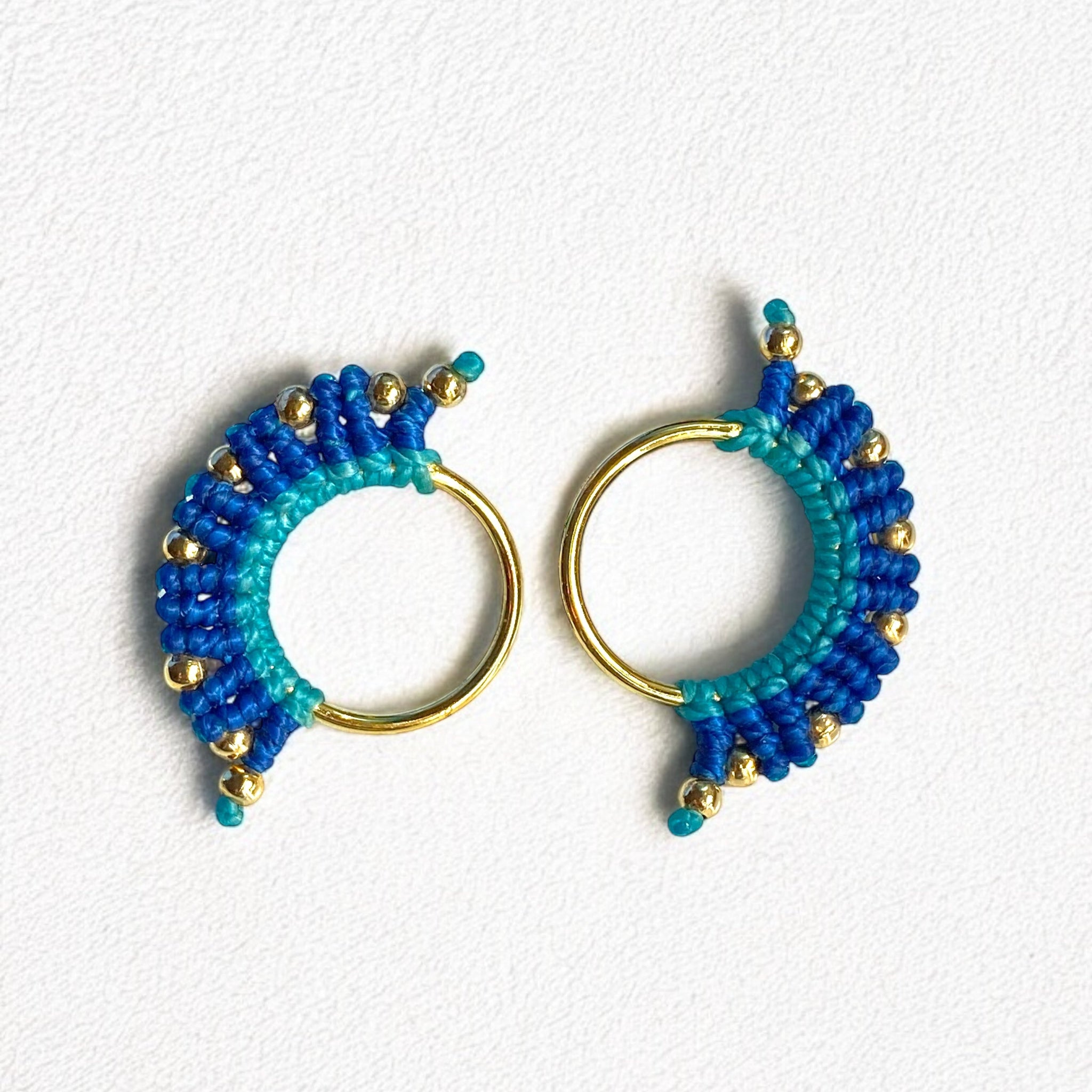 Orecchino macramè nei toni del blu e dell’azzurro, con fili intrecciati a mano e accenti dorati, ripreso in primo piano