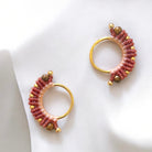 Dettaglio di un orecchino macramè con filato rosa e color terra cotta, intrecciato a mano con un tocco di eleganza dorata